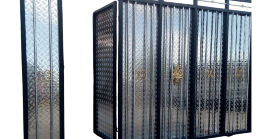 A modern, heavy-duty metal main gate featuring a sliding mechanism, textured steel privacy sheets, structural vertical bars, and an integrated wicket door for convenient pedestrian access.