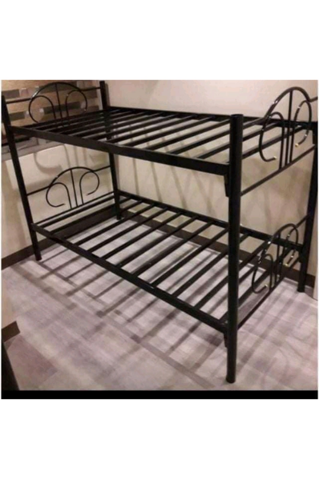 A space-saving, heavy-duty twin-over-twin metal bunk bed frame with built-in metal mattress slats and ornamental arched headboards. Ideal for hostels, dormitories, and shared bedrooms.